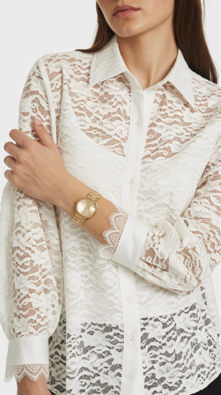 White lace blouse with puffy sleeves, floral embroidery, and vintage detail, styled with jeans while walking through a flower market.