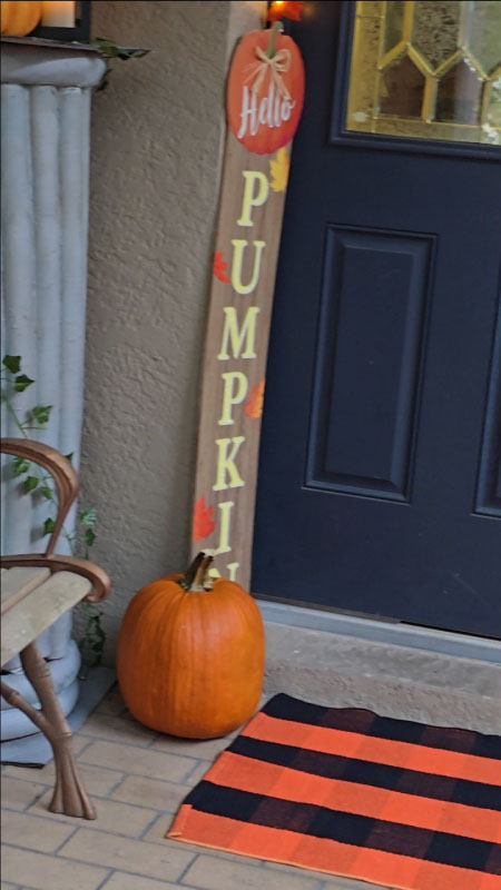 Vertical “Hello Pumpkin” sign and stacked pumpkin sign framing the doorway.