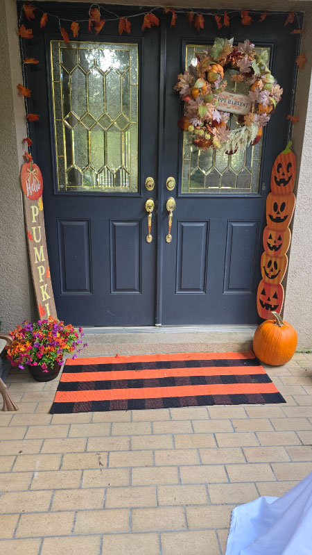 Black-and-orange plaid rug placed at the doorway, pulling the fall theme together.