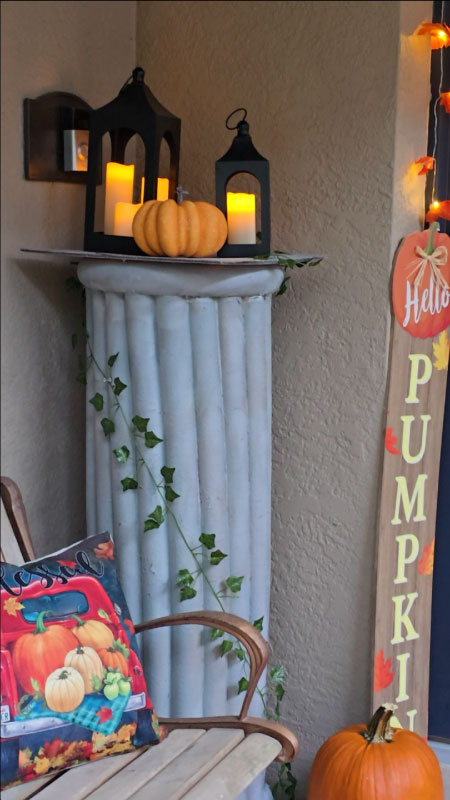 Decorative faux column made from pool noodles and ivy, standing beside the front porch.