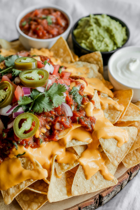 loaded nacho board with cheese jalapenos salsa guacamole and party toppings