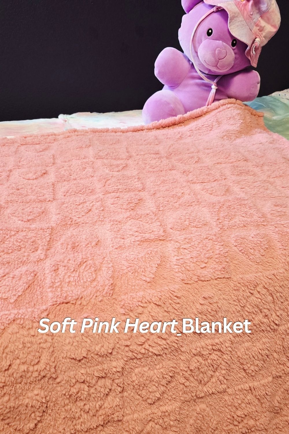 Soft pink heart baby blanket draped over pack and play in girls room makeover with plush texture and cozy design