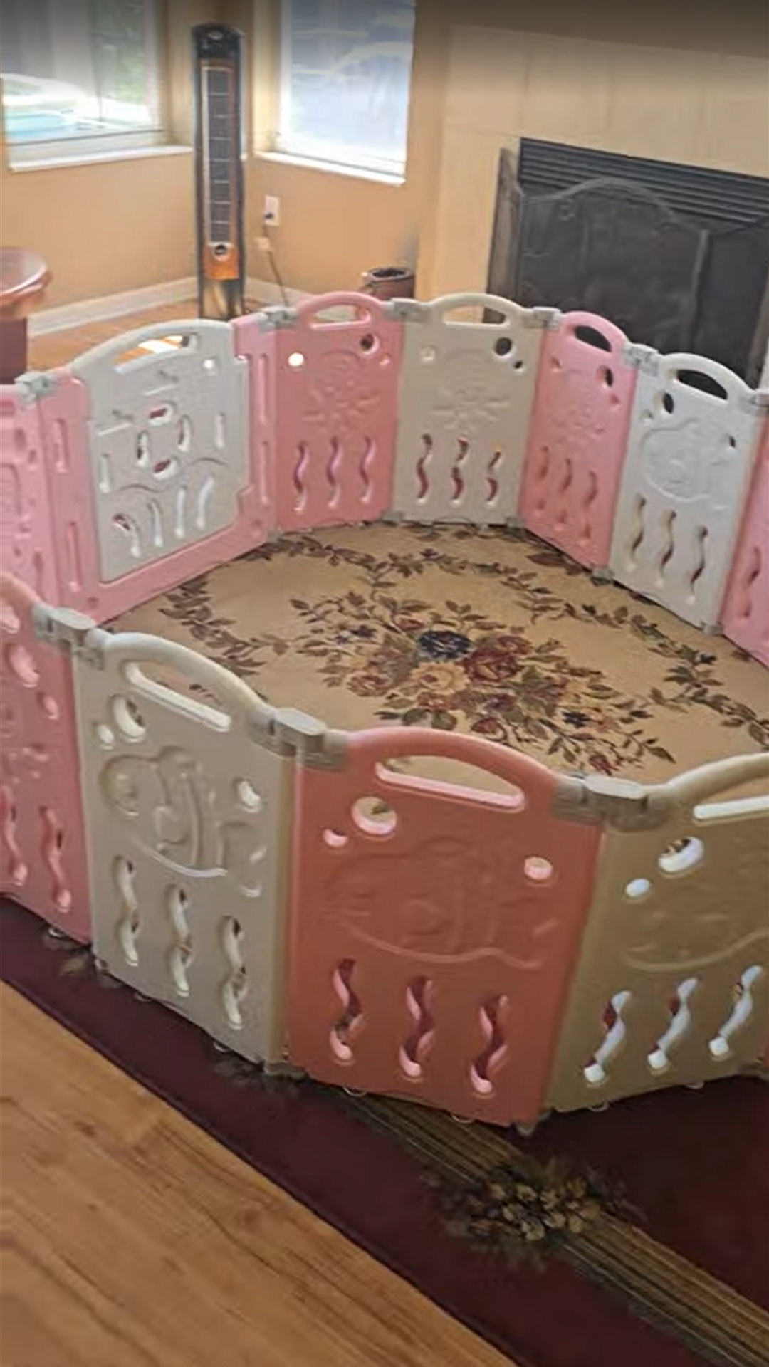 Pink and white foldable baby playpen with activity panel and safety gate for indoor play area