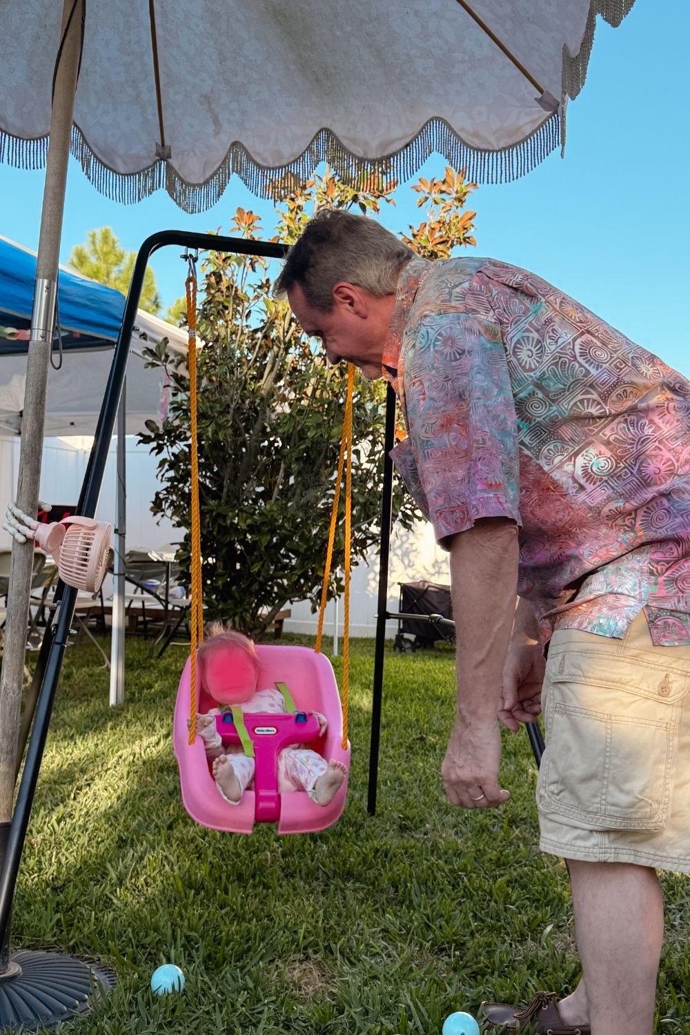 Man pushing little girl in pink swing at backyard birthday party, girls room makeover ideas lifestyle moment