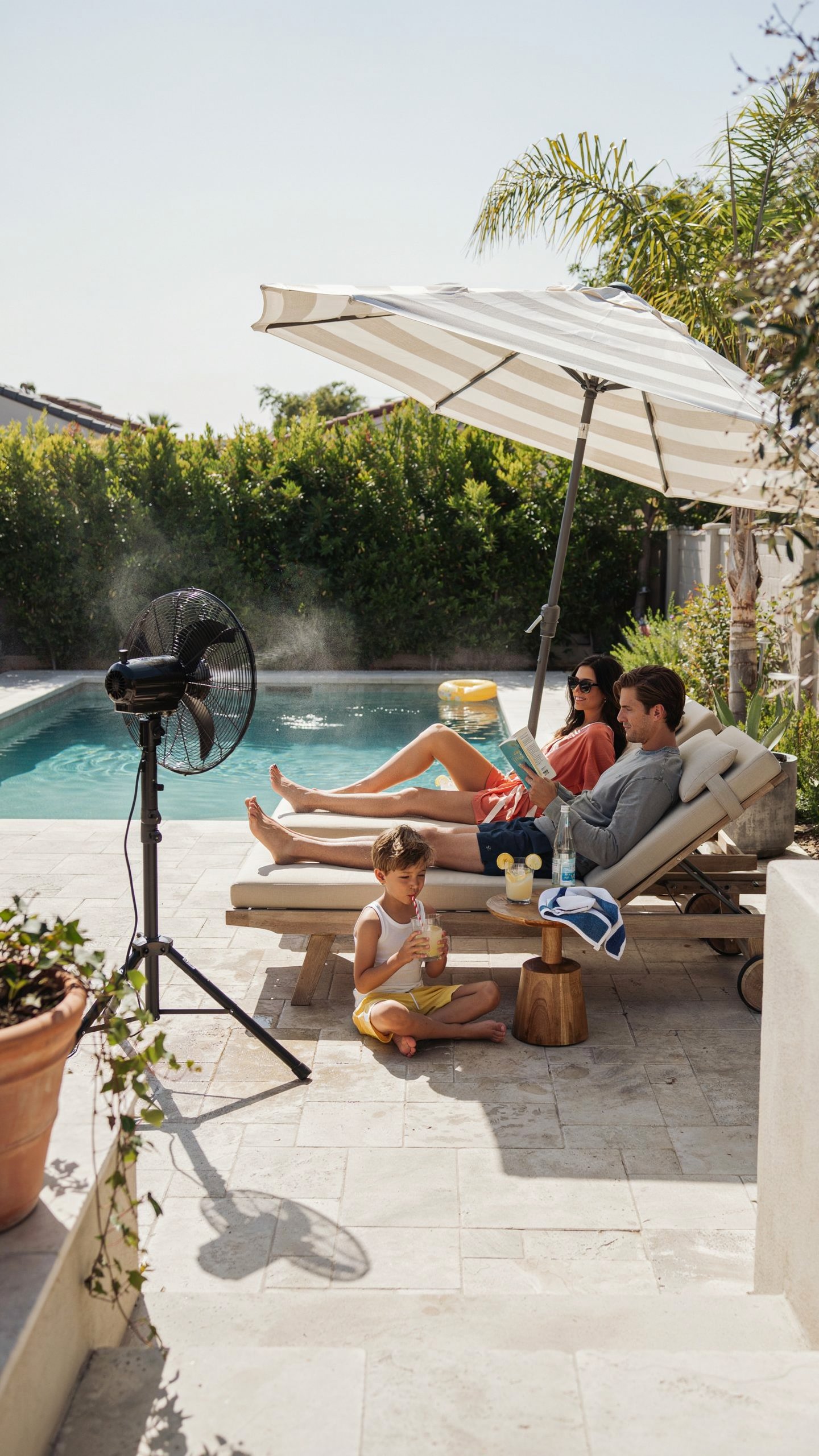 Outdoor misting fan cooling a poolside patio while family relaxes during a hot summer afternoon